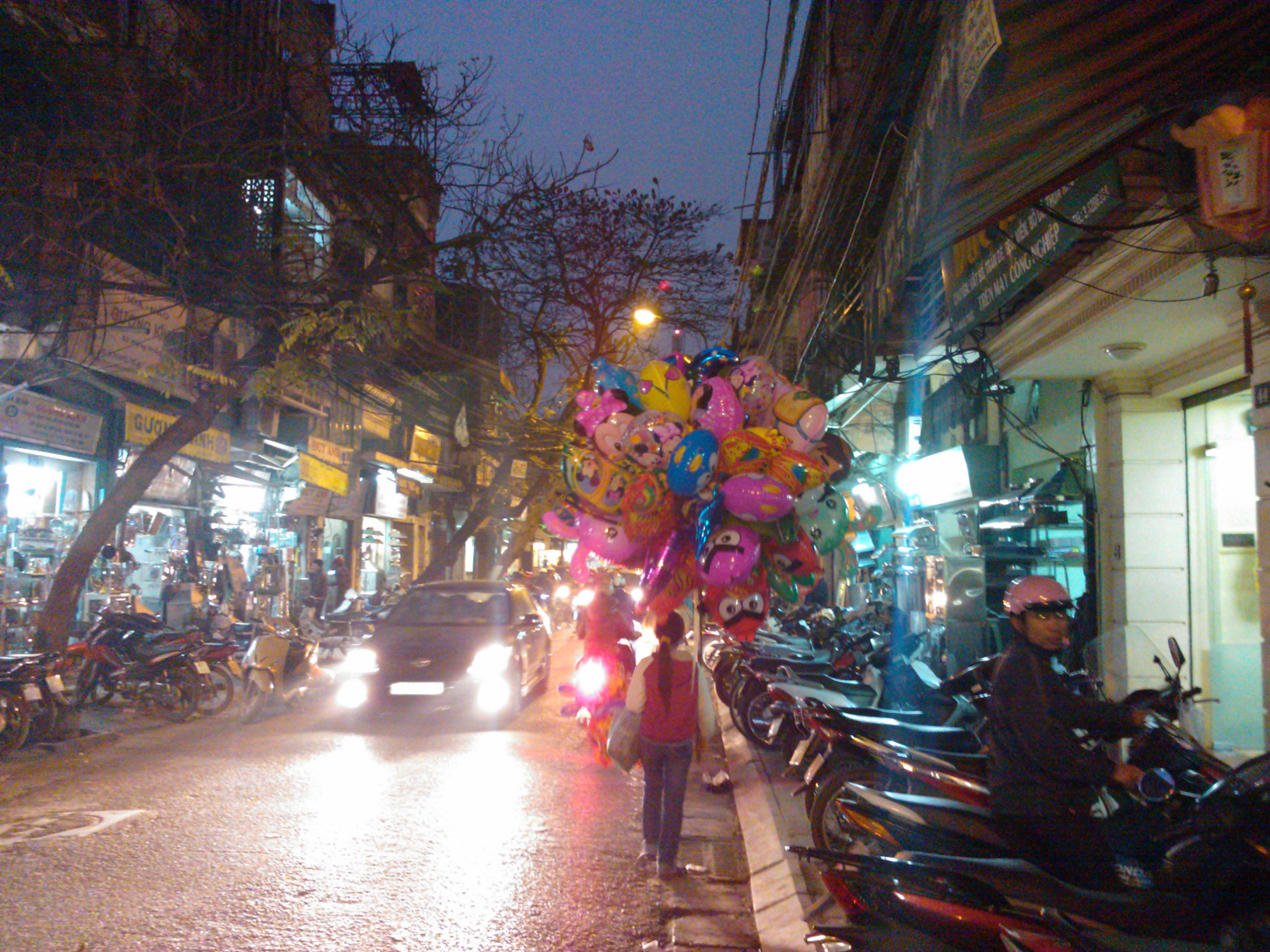 A young girl carrying balloons at night